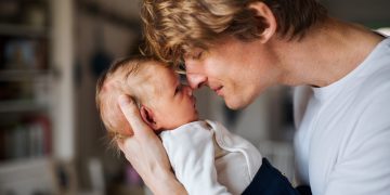 A happy young father with a newborn baby son at home.