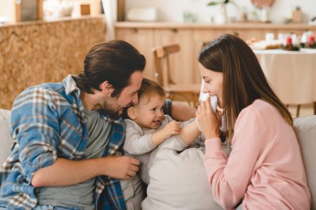 Young loving family playing with little small child kid son daughter toddler, hugging and embracing at home. Child care and parenthood concept